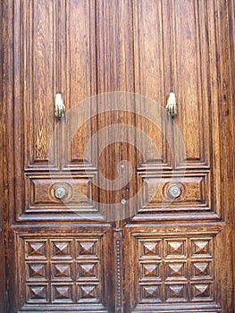 Old, classic and large wooden door with two metal hands used to knock on the door