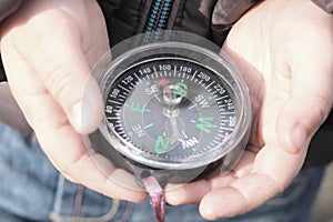 Old classic navigation compass in childs hands on natural background