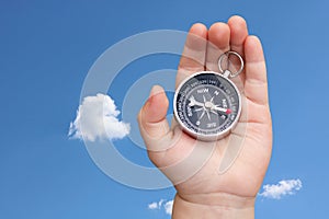 Old classic navigation compass in hand against blue sky background