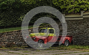 Old classic veteran car with silver red yellow colors and stone wall