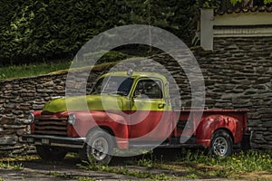 Old classic veteran car with silver red yellow colors and stone wall