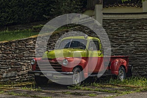 Old classic veteran car with silver red yellow colors and stone wall