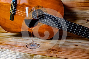 Old classical guitar on wooden background and a glass of wine