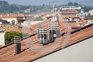 Old clay chimney pots and brick chimney stacks on old tiled roof complete with TV aerials in England, UK.