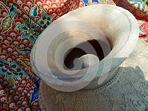 Old clay jar on red and green Batik fabric background