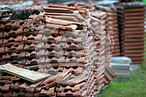 Old clay tile roof tiles stacked on wooden pallets. The background for construction restoration and logistics
