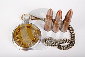 Old clock and ammunition on a white table. Explosive material and time measure