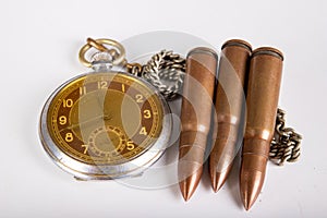 Old clock and ammunition on a white table. Explosive material and time measure