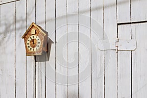 Old clock on a wooden light wall. Vintage clock. Cuckoo clock