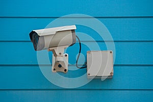 Old Closed Circuit Television Camera or Security CCTV camera setting on blue wooden background.