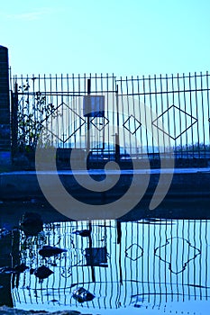 Old closed metal gates and their reflection in the water. Symbolism. Thoughtfulness. I photo