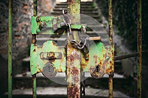 Really old, closed and rusty green iron gate with chain and padlock