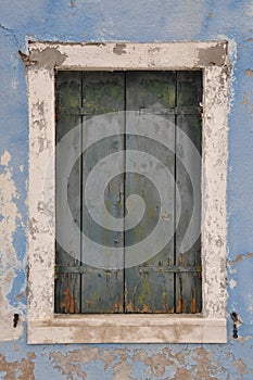 Old closed window with shutter on blue wall