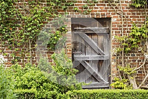 Old Closed Wooden Door in a Brick Wall in a Garden
