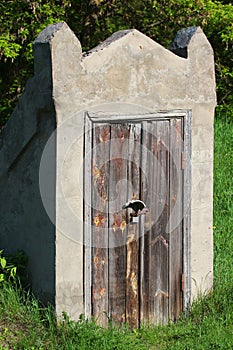 Old closed wooden door to underground stone cellar