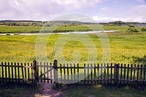 Old closed wooden gate with a fence in summer Sunny day