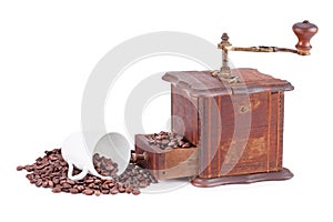 Old coffee grinder and cup with coffee beans .
