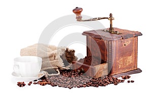 Old coffee grinder and cup of coffee.