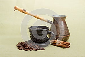 Old coffee pot, black cup with coffee, cinnamon, coffee beans