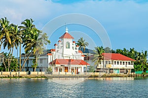 Old colonial Saint Thomas catholic church on the coast of Pamba river, with palms, Alleppey, Kerala, South India