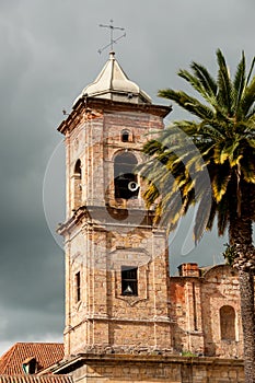 Old colonial stone church tower with palm tree