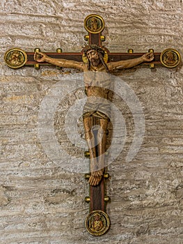 An old colored crucifix from the 15th century on a stone wall