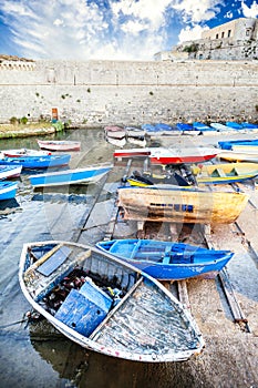 Old colored wooden boats in the small harbor. The Angevin castle in Gallipoli