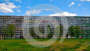 Old communist style block of flats with trees in front of them and large grassland