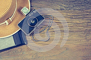 Old compact camera with flash cube, womens hat and black photo album on wooden background. Travel concept.