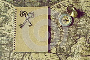 Compass, antique keys and notebook on blur vintage world map, journey concept, copy space