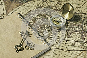 Compass, antique keys and notebook on blur vintage world map, journey concept, copy space