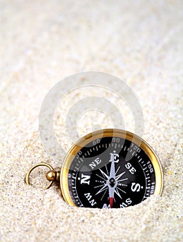 Old compass buried in sand ,