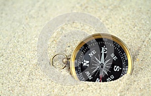 Old compass buried in sand ,
