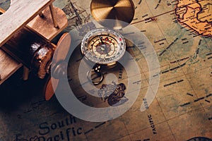 Old compass discovery and wooden plane on vintage paper antique world map