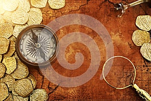 Old compass and gold coins treasure over antique map. top view