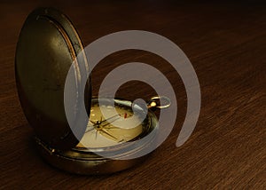 Old compass on a wooden table. 3D illustration of an old metal compass over wooden table.