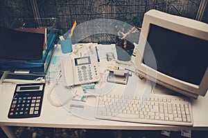 Old computer and phone and calculator on table in office.