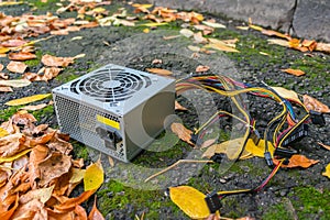 Old computer power supply discarded in a landfill in autumn foliage