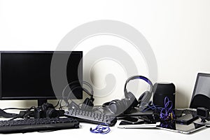 Old computers, digital tablets, mobile phones, headphones, many used electronic gadgets devices on white table. E-waste