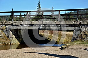 Old concrete bridge with a wooden brown railing on steel girders. frost weathering of concrete structures, falling whole pieces in