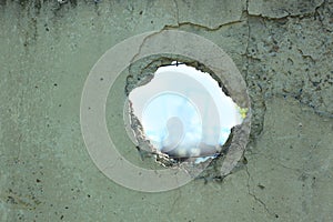 Old Concrete fence with hole on blue sky view. Wall with broken tiles, use as horror scene, background for breaking news