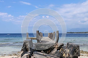 Old concrete pier on the beach on Gili Meno, Lombok, Indonesia. Broken Concrete Pier or Jetty and Rocks on Blue Sea. View of broke