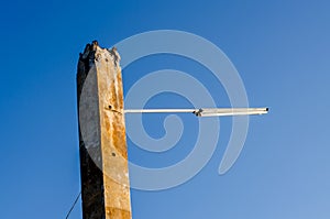 Old concrete pole and lamp on blue sky