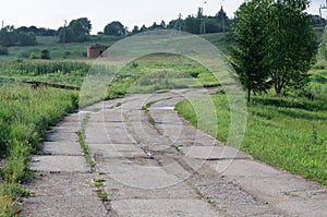 Old concrete road leaving far into the distance among meadows