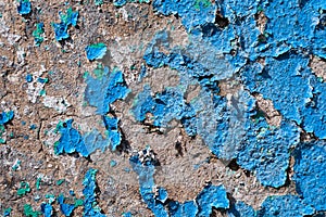 An old concrete wall with blue peeling paint. Texture of exfoliating paint from the wall