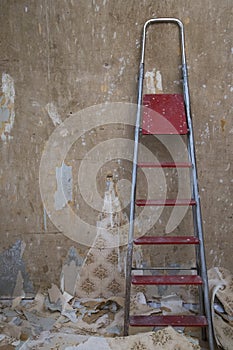 Old concrete wall with removed wallpaper and a ladder