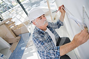 Old construction worker measuring wall