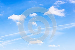 Old contrail between cumuli clouds in blue sky