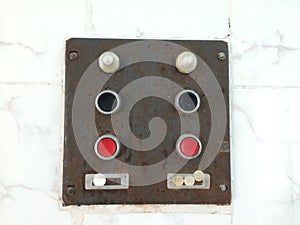 Old control unit with red and black buttons. Iron rusty board with mass switch and current supply