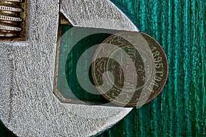 Old copper coin in a swivel key on a green background